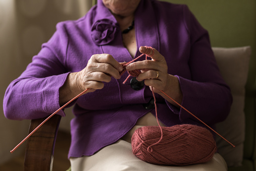 Close up senior womens hands knitting at home