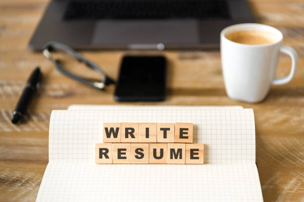 istock Closeup on notebook over wood table background, focus on wooden blocks with letters making WRITE RESUME words 959720844