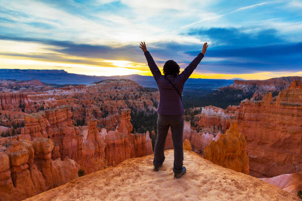 On top of Bryce Canyon with hands raised woman celebrates On top of Bryce Canyon with hands raised bryce canyon stock pictures, royalty-free photos & images