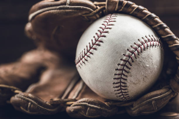 Vintage baseball gear on a wooden background A group of vintage baseball equipment, bats, gloves, baseballs on wooden background baseball sport photos stock pictures, royalty-free photos & images
