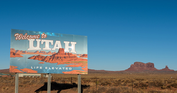 Welcome to Utah sign withblue sky and butte in the background