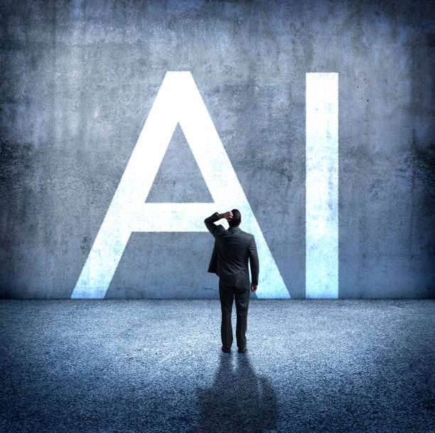 Man Concerned By Implications Of Artificial Intelligence A rear view of a man standing with his hand on top of his head as he stands below the large letters, "AI" which stand for artificial intelligence. He is concerned about the unknown implications of the rollout of artificial intelligence on our society. worried man standing stock pictures, royalty-free photos & images