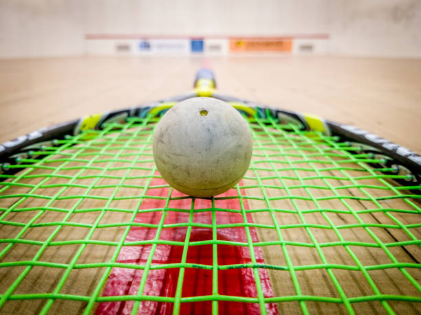 weiße squash ball auf den saiten eines schlägers in der mitte einen indoor squash-court - squash racket stock-fotos und bilder