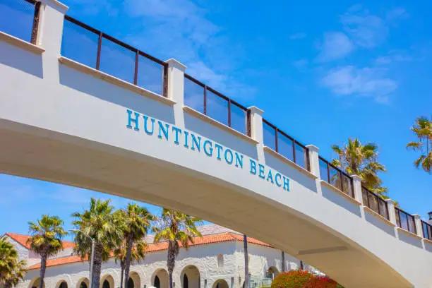 A stock photo of the Huntington Beach sign on a pedestrian bridge. Photographed in Huntington Beach, California.