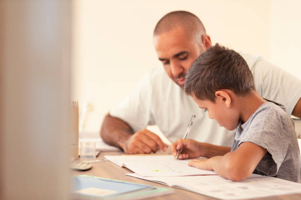 istock Young Aboriginal boy doing homework with the help of his father. 959758002