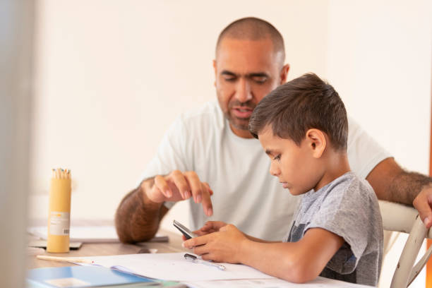 istock Young Aboriginal boy doing homework with the help of his father. 959758008