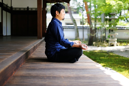 A man meditating at a temple on a sunny day.