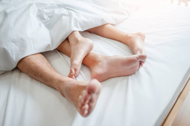 istock Love lying in bed in hotel,embracing on white sheets, close up legs. 959776730