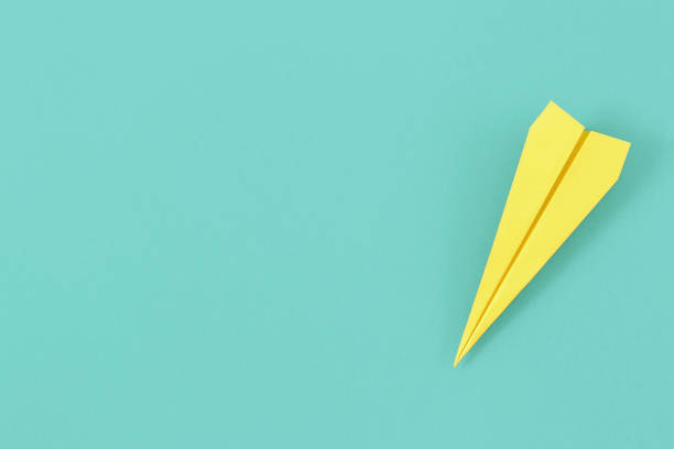 istock Flat lay yellow paper plane on pastel blue background with copy space. Top view creative travel background concept 959779834