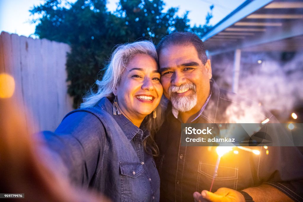 Casal mexicano sênior, segurando Sparkler ao tomar um Selfie - Foto de stock de Casal royalty-free