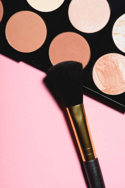 top view of different blushes palette with brush on pink surface