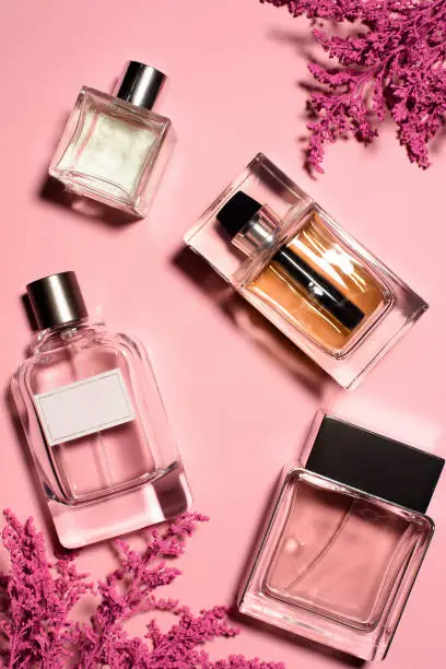 Photo of top view of bottles of perfumes with pink flowers