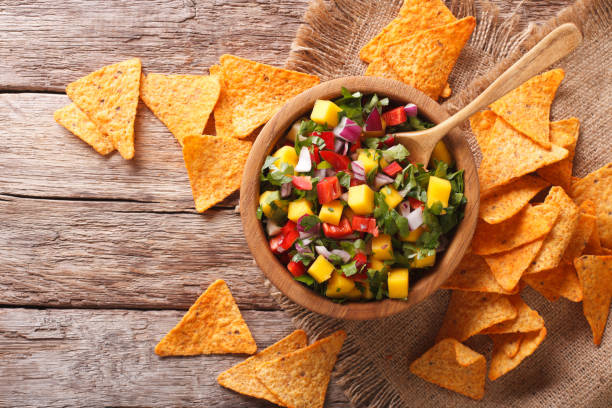 istock Delicious salsa with mango, chilli pepper, cilantro and onion in a bowl and nachos. Horizontal top view 959787752