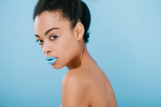 istock seductive young woman with creative makeup and blue lips looking at camera isolated on blue 959790706