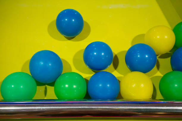 Plastic ball in various colors against yellow background of game machine.