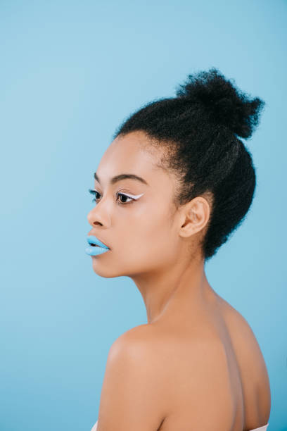 istock attractive young woman with creative makeup looking away isolated on blue 959792224