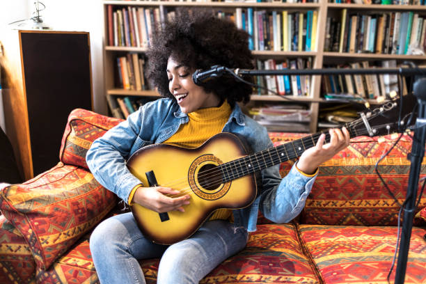 istock Happy african woman singing and playing a guitar in studio 959811298