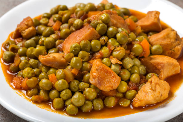 Chiken stew with peas, carrot and tomato sauce on plate stock photo