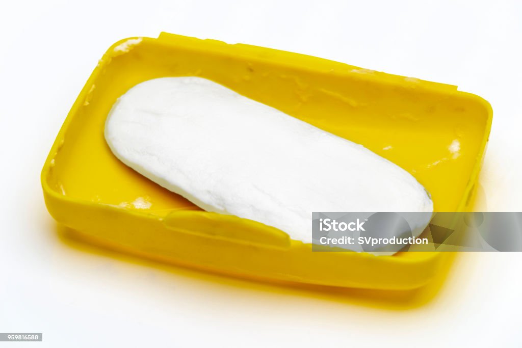 Soap in the soap dish Soap residue in a yellow plastic soap dish on a white background. Leftovers Stock Photo