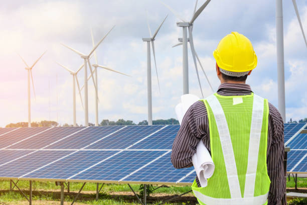 ingeniero de hombre joven con casco amarillo en el panel solar y el viento generadores planta construcción sitio fondo - solar panel engineer solar power station solar energy fotografías e imágenes de stock