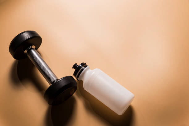 istock Gym dumbbell with sport bottle on yellow background 959823246