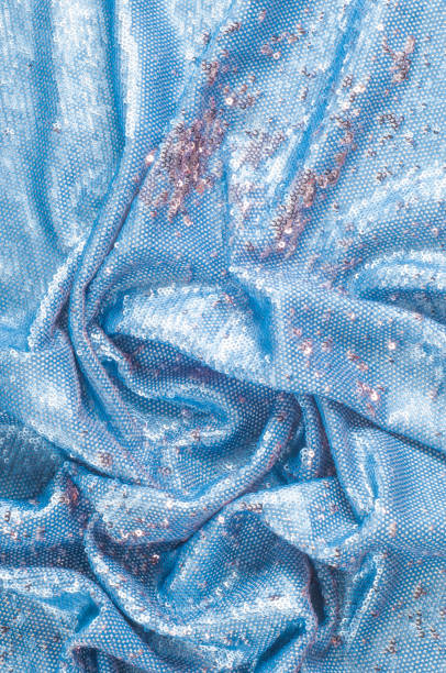 istock Texture, background, pattern. Silk fabric of blue color embroidered with sequins, sparkles reflects the rays of the sun 959828160
