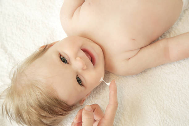 istock Baby handling: Woman applying moisturizing cream on her baby's face 959831494