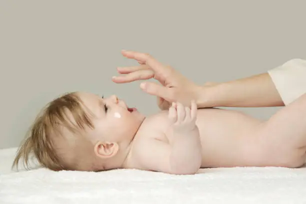 Baby handling: Woman applying moisturizing cream on her baby's face