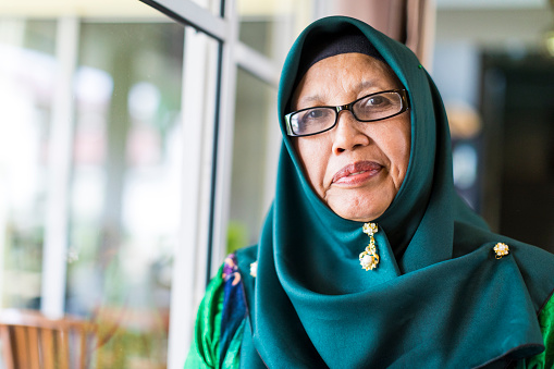 Elderly Malaysian woman looking towards the camera while waiting for someone.