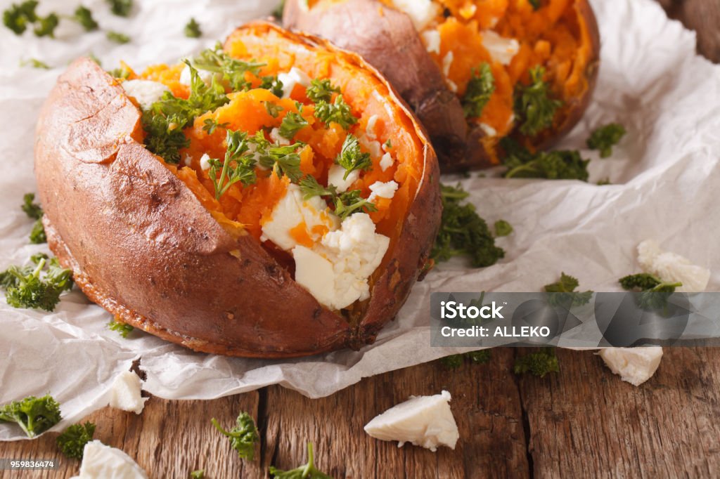 healthy food: baked sweet potato stuffed with cheese and parsley close-up. Horizontal healthy food: baked sweet potato stuffed with feta cheese and parsley close-up on the table. Horizontal Baked Stock Photo