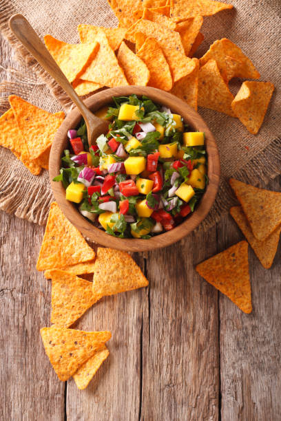istock Delicious salsa with mango, chilli pepper, cilantro and onion in a bowl and nachos. Vertical top view 959836852
