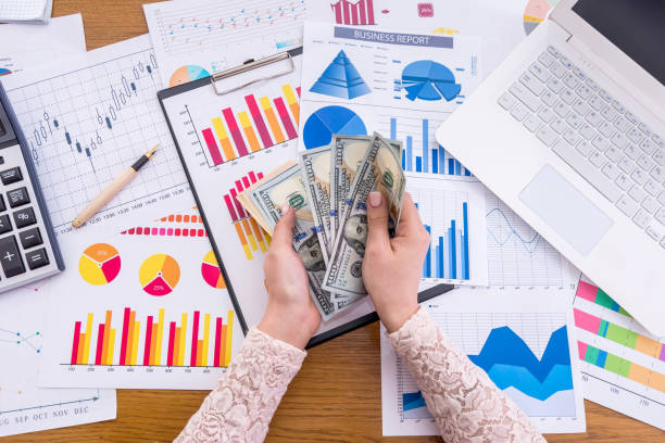 istock Female hands with dollar on business graphs background 959839322