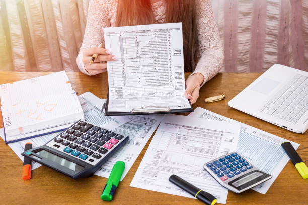 istock Woman looking through 1040 form preparing to fill 959842336