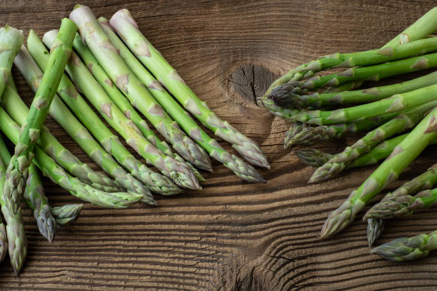 istock Raw garden asparagus stems. Fresh green spring vegetables on wooden background. (Asparagus officinalis). 959849100