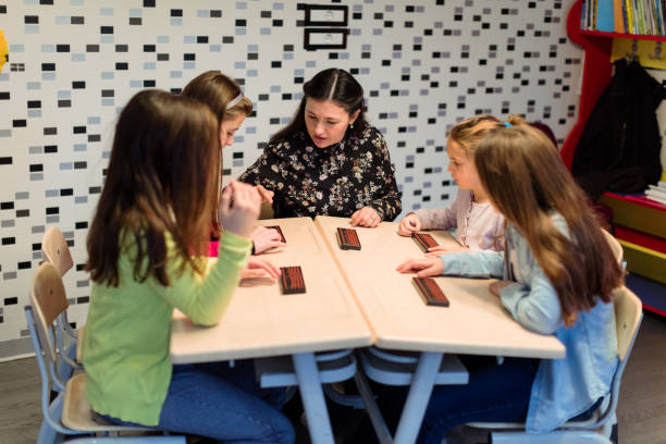 istock Group of school children learning abacus with teacher 959855478