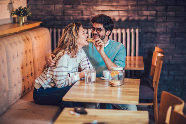 istock Beautiful loving couple sitting in a cafe sharing cookie 959856074