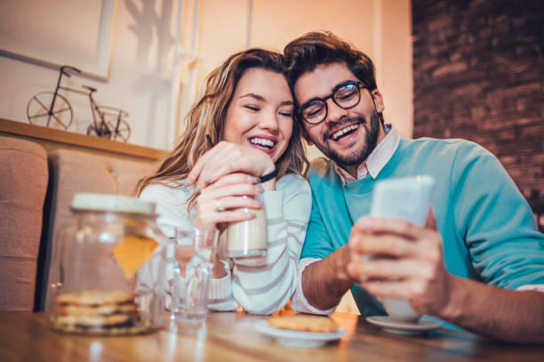 istock Couple sitting in a cafe drinking coffee and using phone 959856860