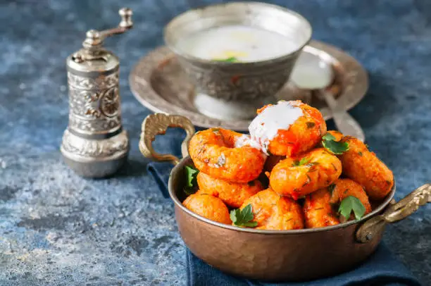 Traditional Turkish food - fellah koftes, polpettes from bulgur and semolina in tomato sauce with parsley and ayran. Middle eastern food concept.