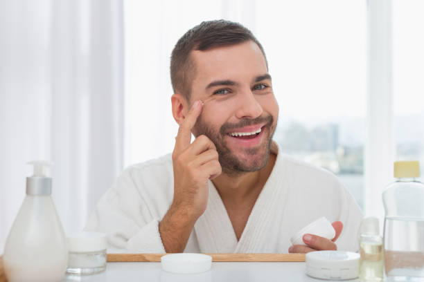 istock Joyful handsome man putting cream on his face 959862088