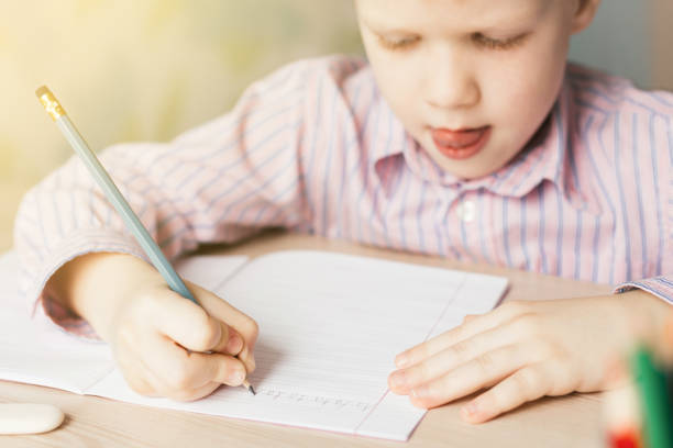 istock Cute little boy writing in notebook at the table. 959862132