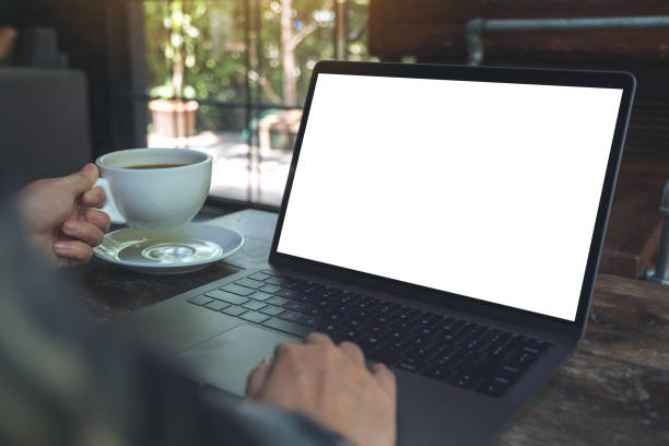 istock Mockup image of a woman using laptop with blank white desktop screen while drinking hot coffee in cafe 959867936