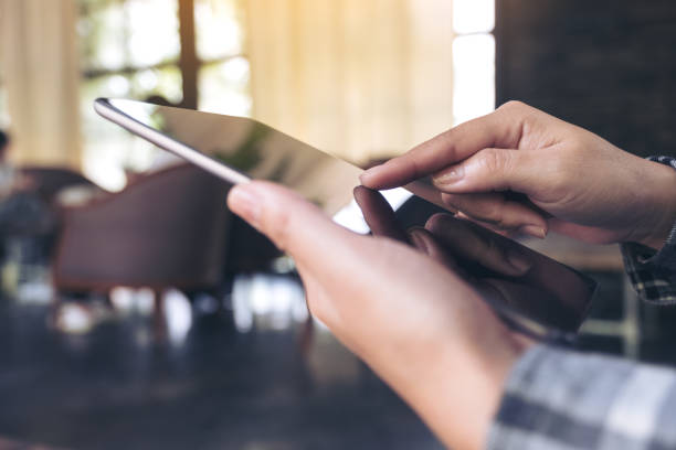 istock Closeup image of hands holding and using tablet pc in modern cafe 959873670