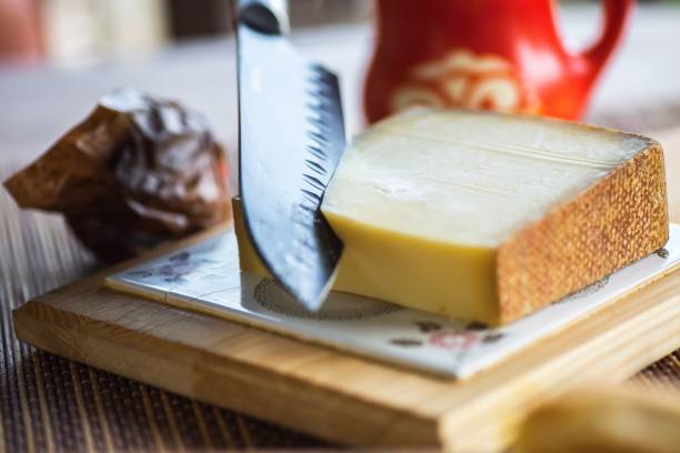 Knife slices cheeseon kitchen board. stock photo