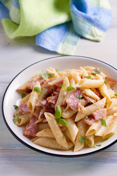 istock Penne pasta with bacon and sundried tomatoes 959880016