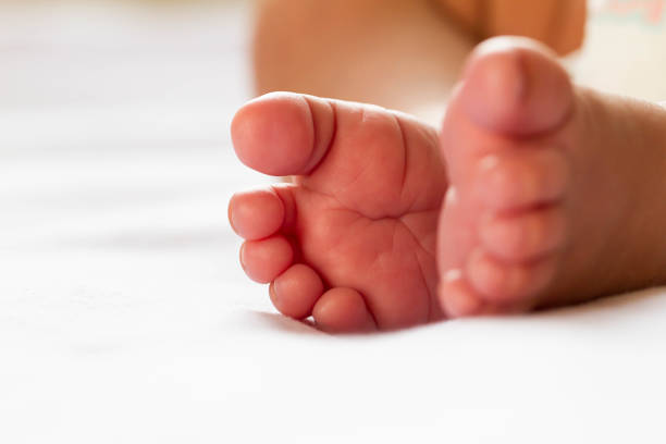 istock Newborn baby infant feet on white bed 959883864