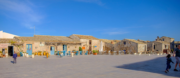 People in Piazza Regina Margherita, the main square of Marzamemi, a small maritime village located by the Ionian Sea coast.