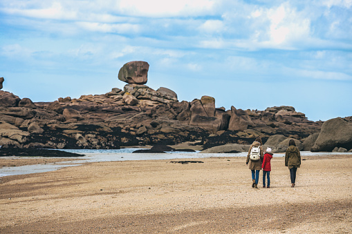family walks by typical Brittany coast at  the Tregastel in the north of France. 