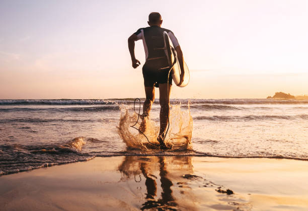 istock Surfer with surfboard runs in to the ocean waves 959889556