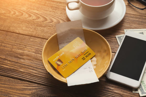 Restaurant bill and credit card on wooden table Restaurant bill for coffee, credit card and blank smartphone on wooden table, paying for lunch at cafe, copy space restaurant table card stock pictures, royalty-free photos & images