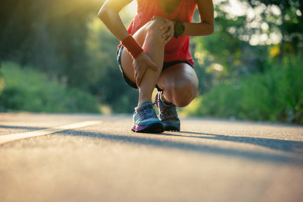 女性のランナーを得たスポーツ傷害森林歩道上で実行 - spasm ストックフォトと画像